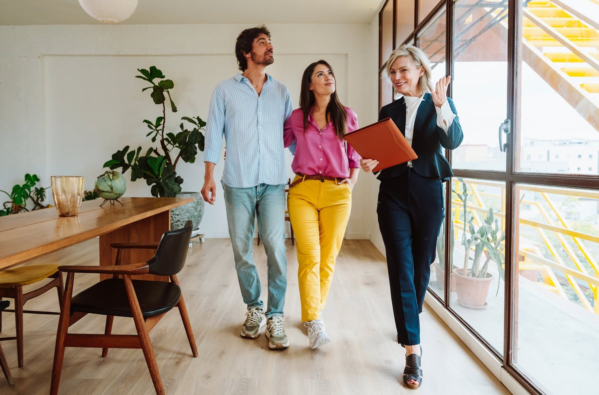 Real estate agent showing a new apartment and features of a good investment to a young couple. Woman and man buying a property in a rich area of the city.